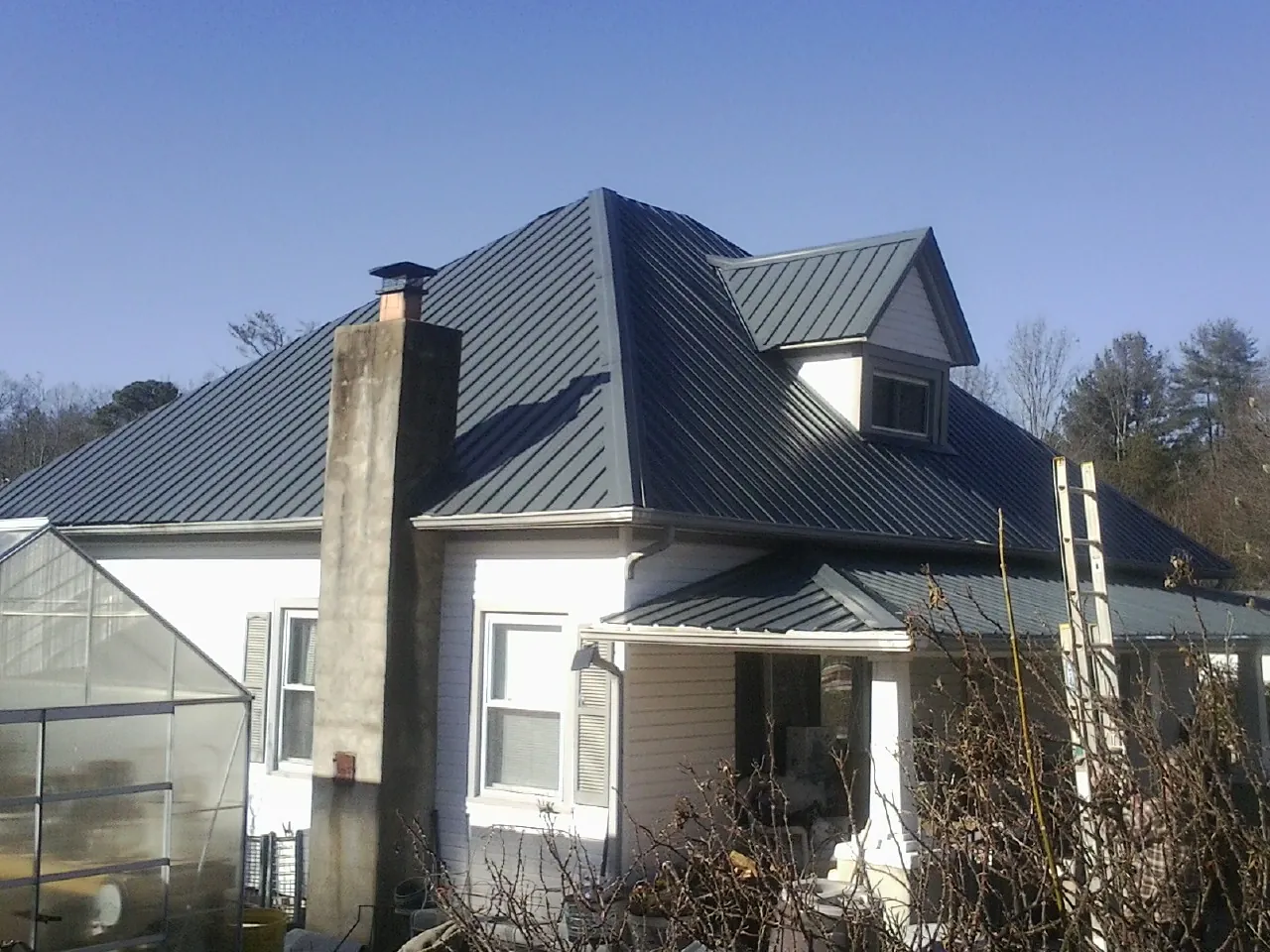 Dark blue standing seam metal roof on a white farmhouse with dormer — Slate & Tile Roof Repair by Roofing Brothers in Sanbornville