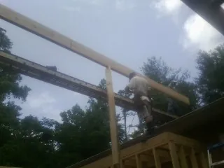 Carpenter setting a ridge beam over a new addition frame — Ice Dam Removal by Roofing Brothers in Sanbornville