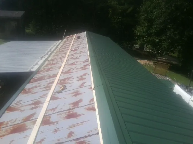 Old rusted panels beside newly installed green metal roofing — Wind Damage Roof Repair by Roofing Brothers in Sanbornville