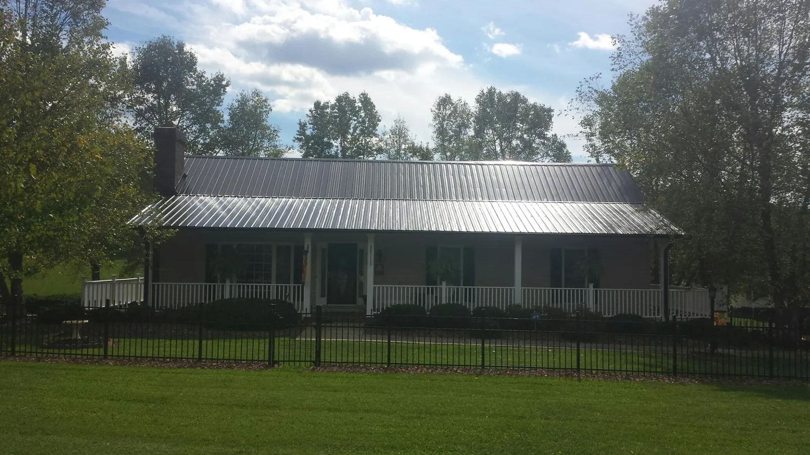 Gray metal roof on a brick ranch with a full width front porch — Gutter Guard Installation work by our crew in Sanbornville