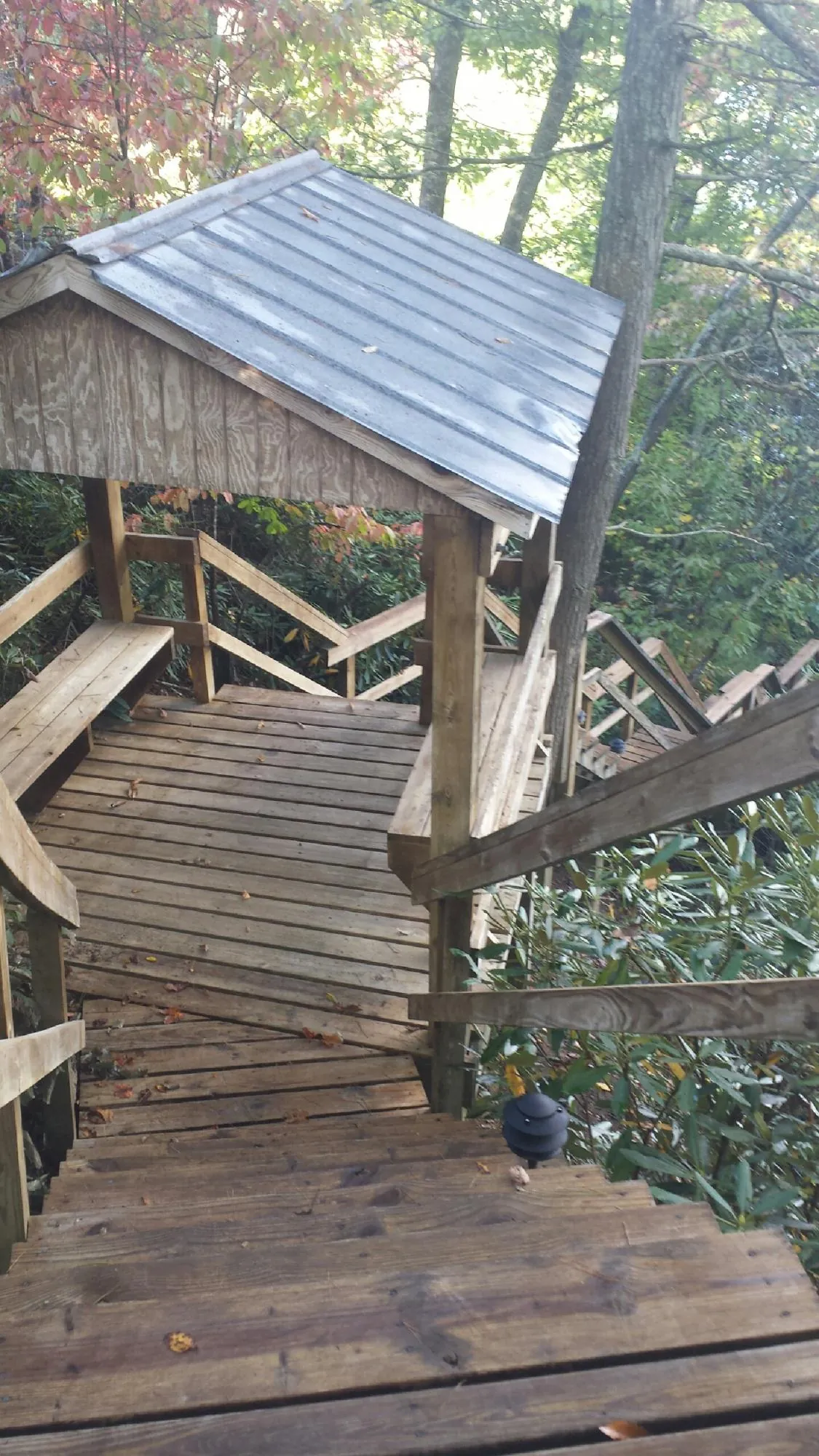 Metal roofed shelter over wooden steps on a wooded walkway — Skylight Repair & Installation work by our crew in Sanbornville