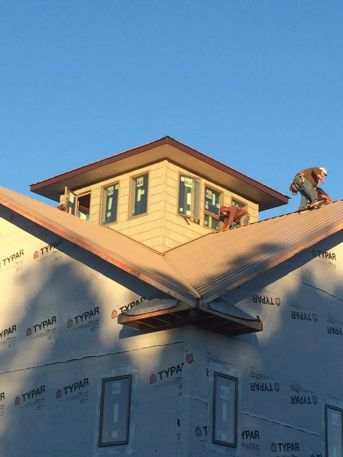 Roofers working around a rooftop cupola on a new metal roof at sunset — Roof Waterproofing in Sanbornville by Roofing Brothers